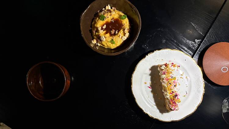 Tyylikkäästi asetellut fine dining -annokset tummalla pöydällä, esillä värikäs jälkiruoka ja pähkinöillä viimeistelty suolainen annos. Tyylikkäästi asetellut fine dining -annokset tummalla pöydällä, esillä värikäs jälkiruoka ja pähkinöillä viimeistelty suolainen annos.