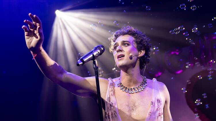 Tomáš Kantor on stage in front of a microphone with bubbles.