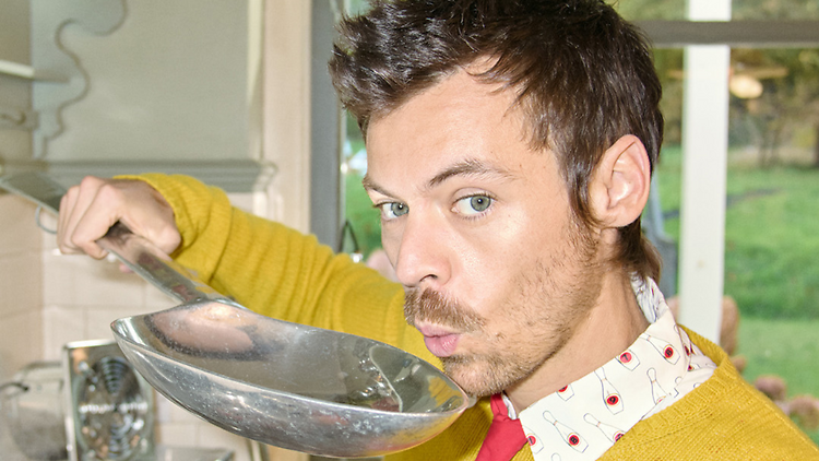 Harry Styles blowing on a giant spoon.