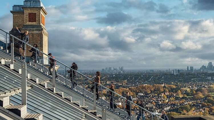 A group of visitors climb the stairs of Summit Ally Pally, with the London skyline in the background