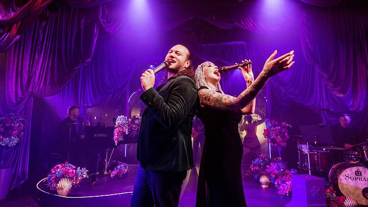 A man and a woman sing back to back on stage