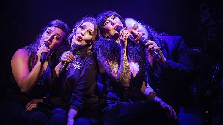 4 women singing with the heads close together