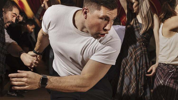 Man in a white t-shirt dancing in a Burns Night ceilidh