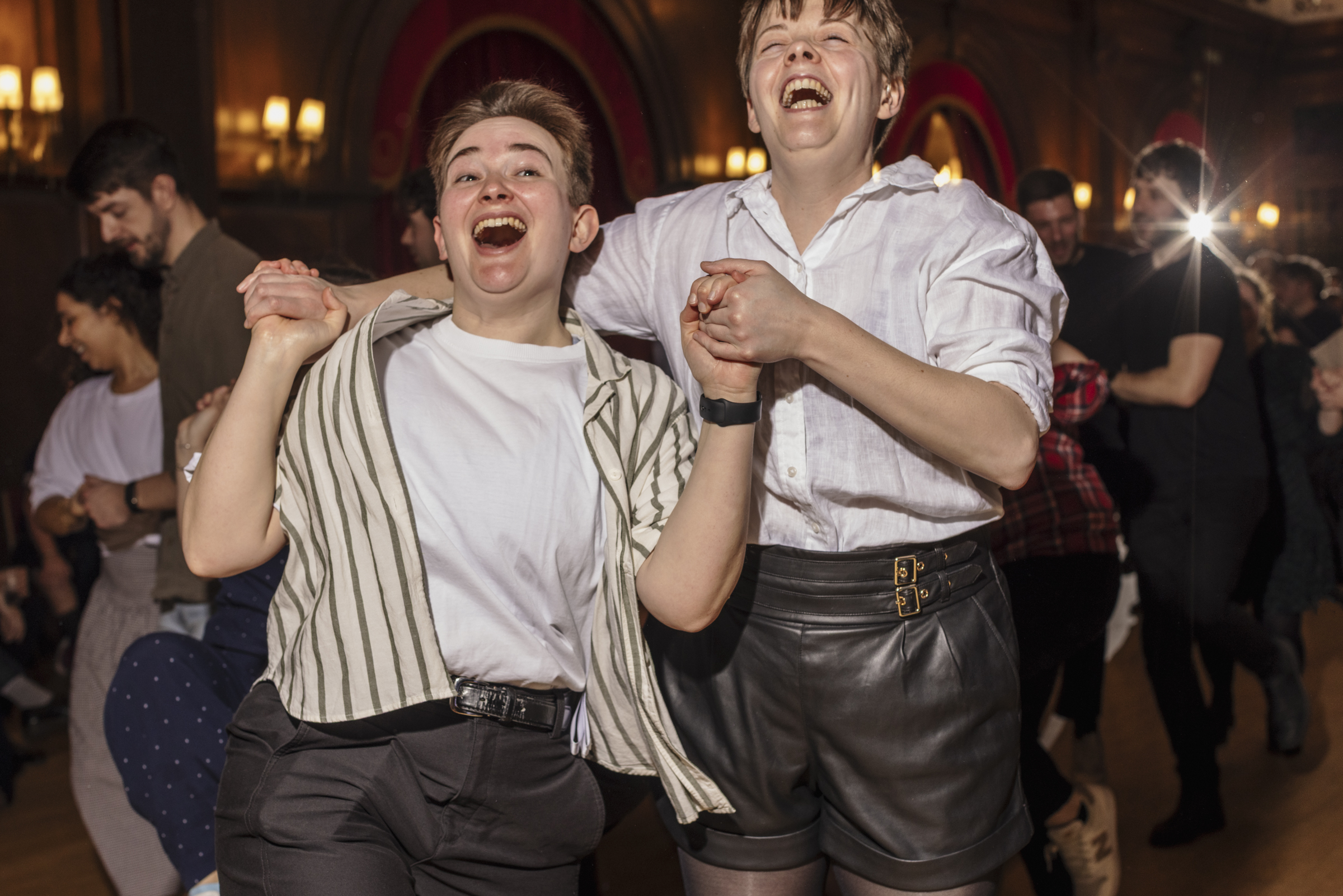 Two people holding hands and grinning while dancing 