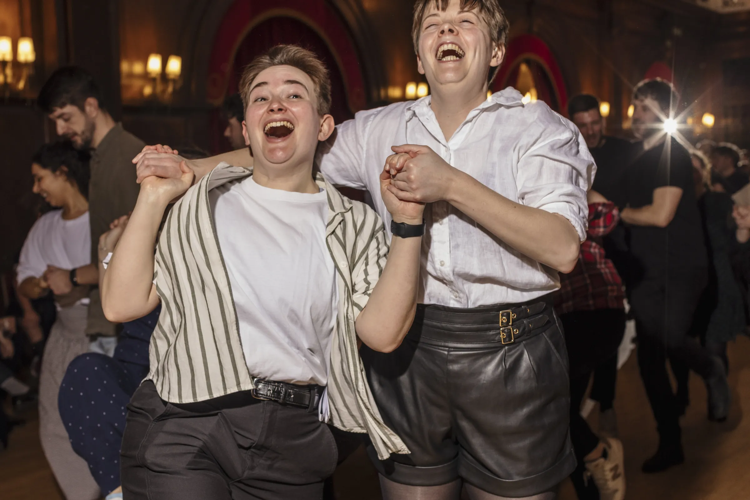 Two people holding hands and grinning while dancing 
