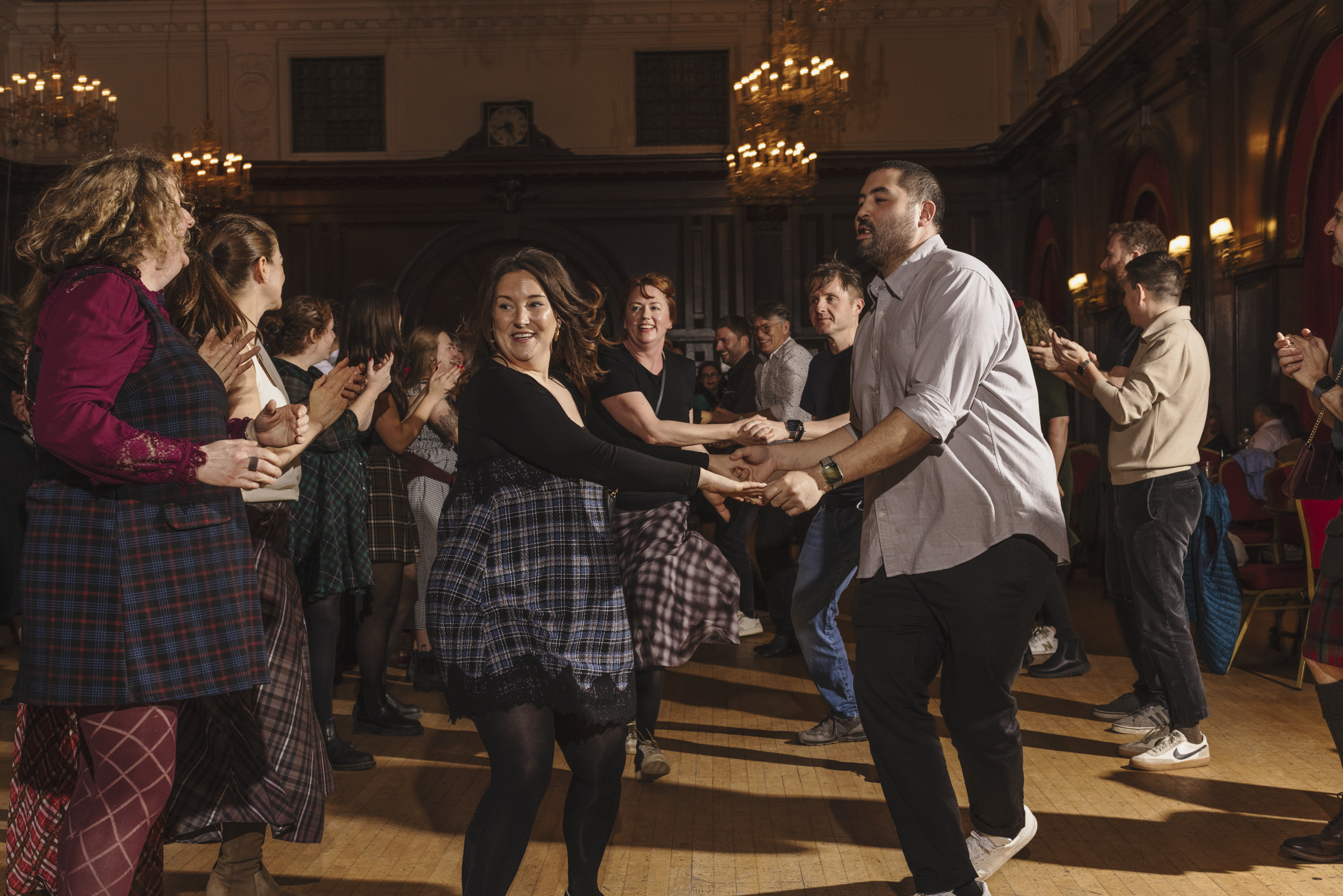 Couples wearing tartan dancing in lines at the ceilidh 