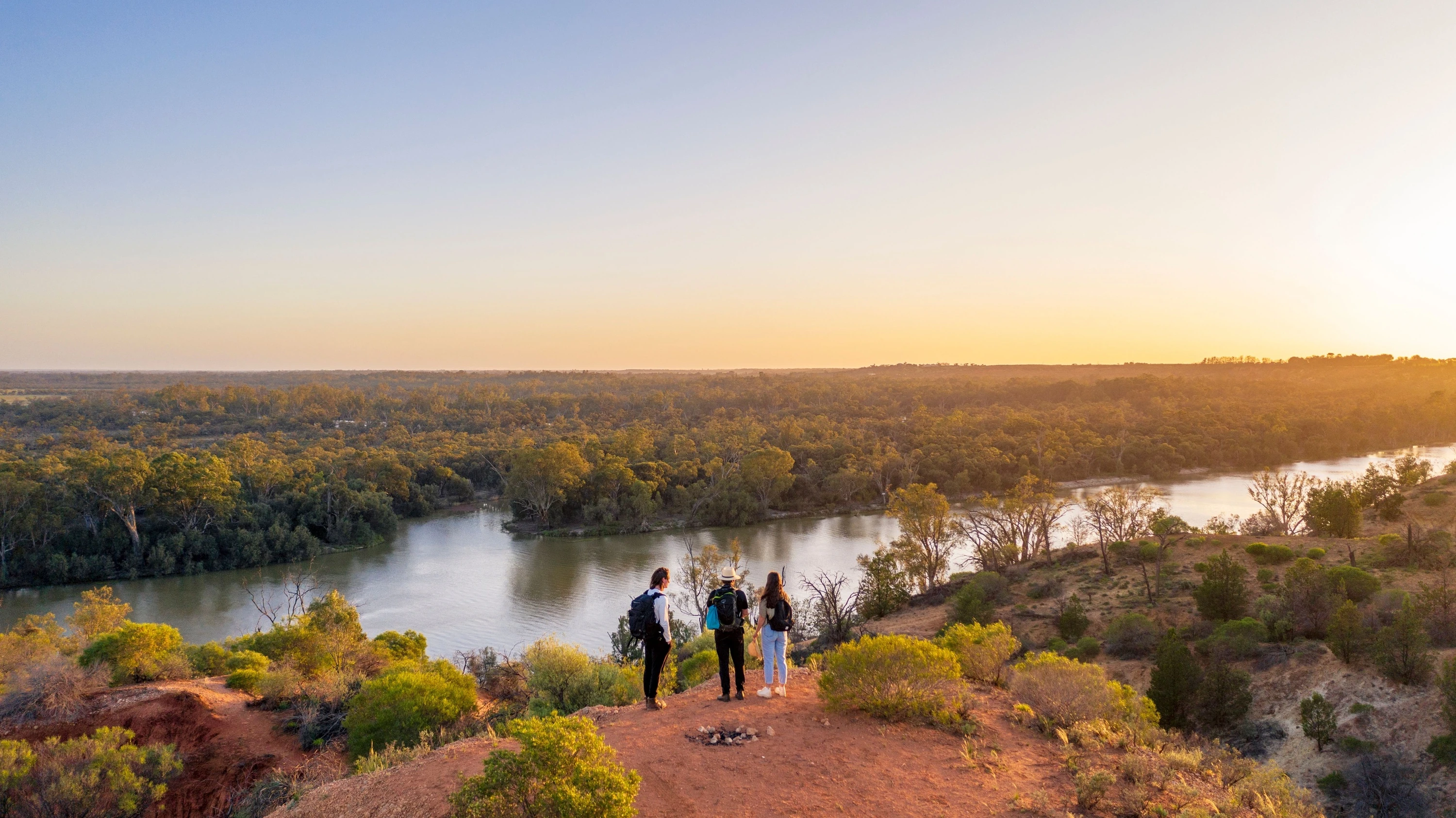 People walking next to river at sunset