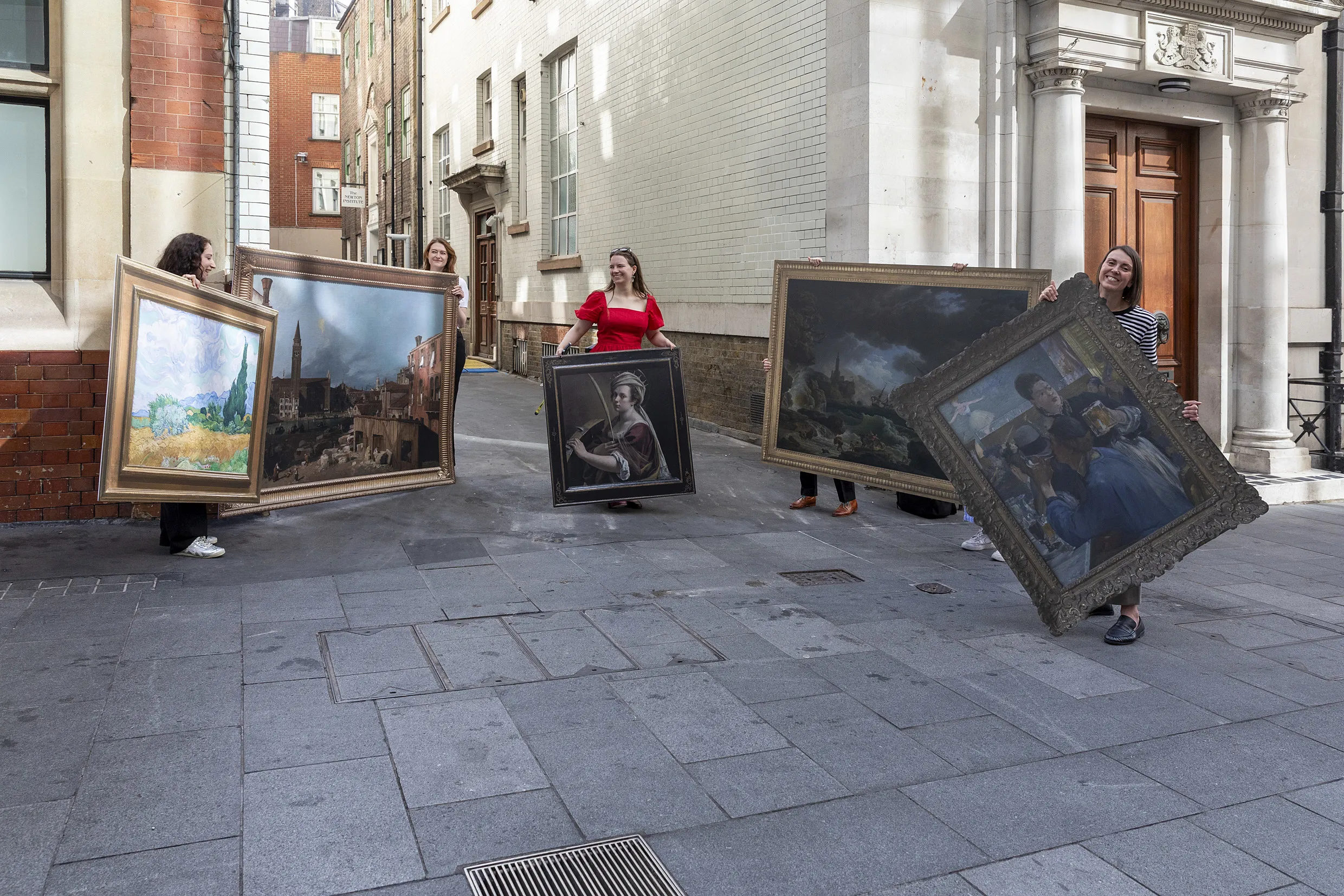 Five people carry life-sized recreations of famous artworks through a sunny London street