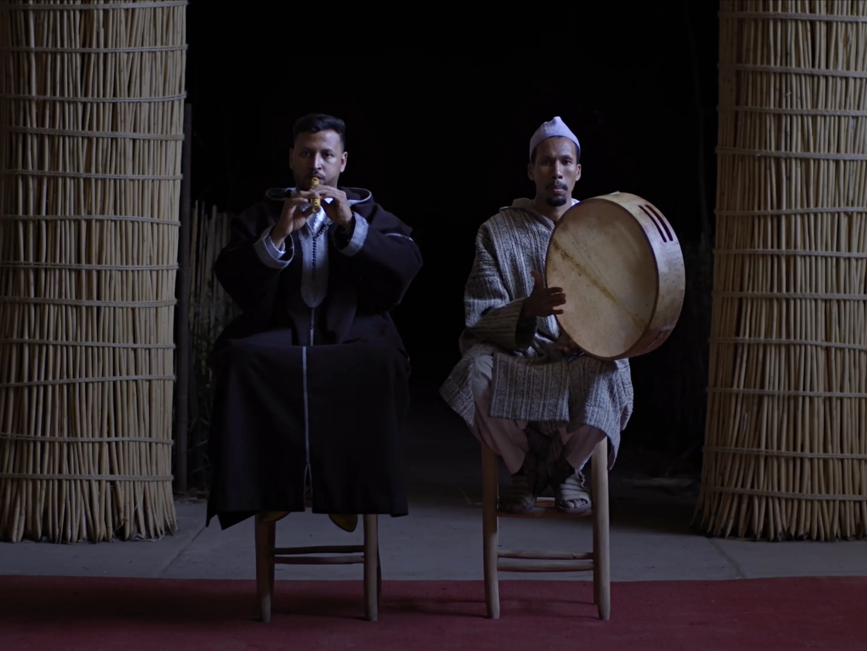 Two men on stools playing instruments