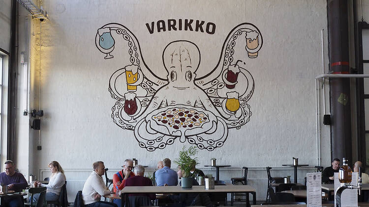 Varikko Panimon sisätila Oulussa, etualalla pöytiä ja taustalla mustekalaa esittävä seinämaalaus.