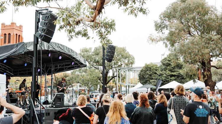 People in car park at outdoor stage.