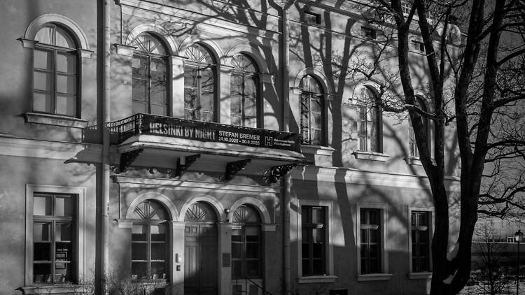 Puun varjo lankeaa uhkaavan näköisenä Hakasalmen huvilan ylle mustavalkoisessa kuvassa Helsingissä