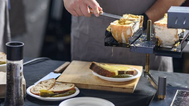Hand scraping melted cheese onto bread