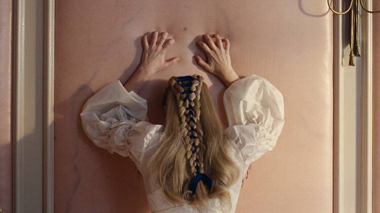 Margot Robbie raapii seinää joka näyttää iholta elokuvassa Humiseva harju