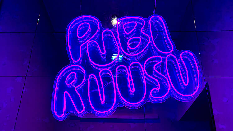 Neonkyltti jossa lukee Pubi Ruusu Neonkyltti jossa lukee Pubi Ruusu