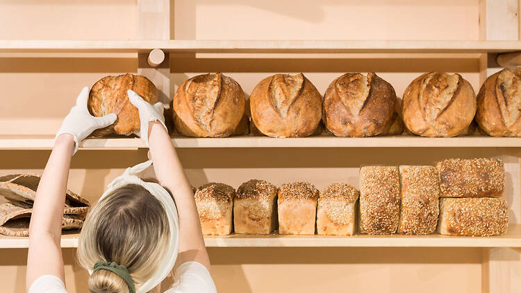 Leipuri asettelee pyöreitä hapanjuurileipiä Bageri Å:n vaaleille puuhyllyille Turussa.