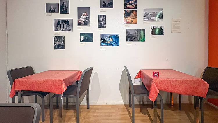 Yksinkertainen ravintola, jossa on valokuvia seinällä ja pöydillä punaiset pöytäliinat Yksinkertainen ravintola, jossa on valokuvia seinällä ja pöydillä punaiset pöytäliinat