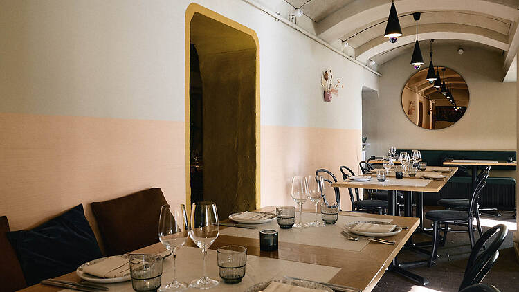 Ravintola Kakolanruusun vaaleasävyinen ja holvimainen ravintolasali, joka on katettu tyylikkäästi illallista varten.