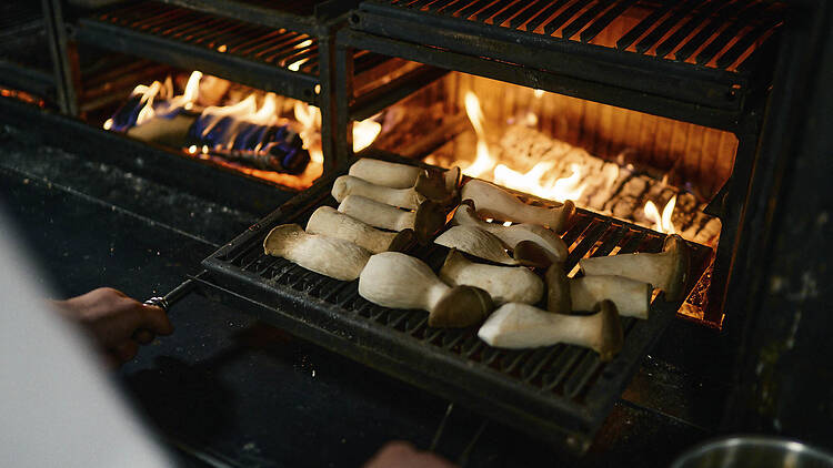 Lähikuva Ravintola Kakolanruusun suuresta avotuligrillistä, jossa ruokaa paahdetaan ritilällä.