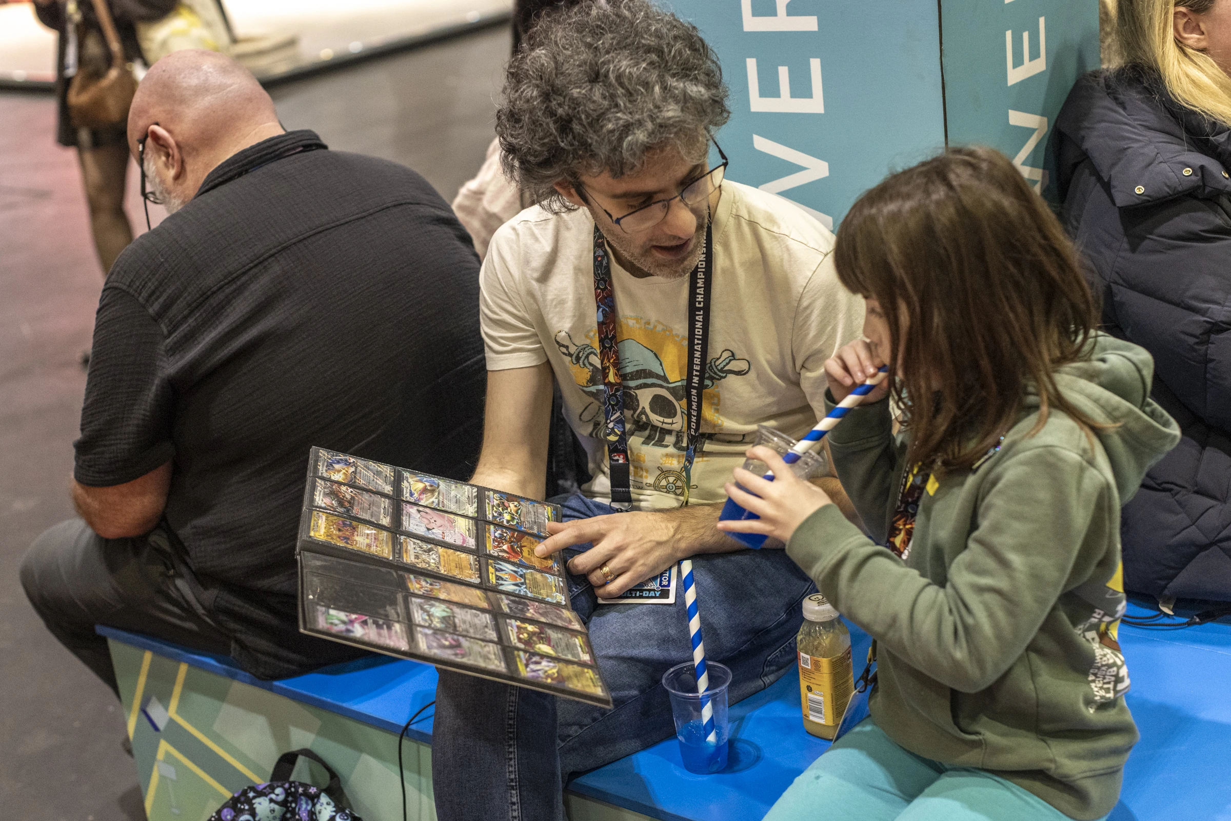 A dad showing his daughter Pokemon cards 