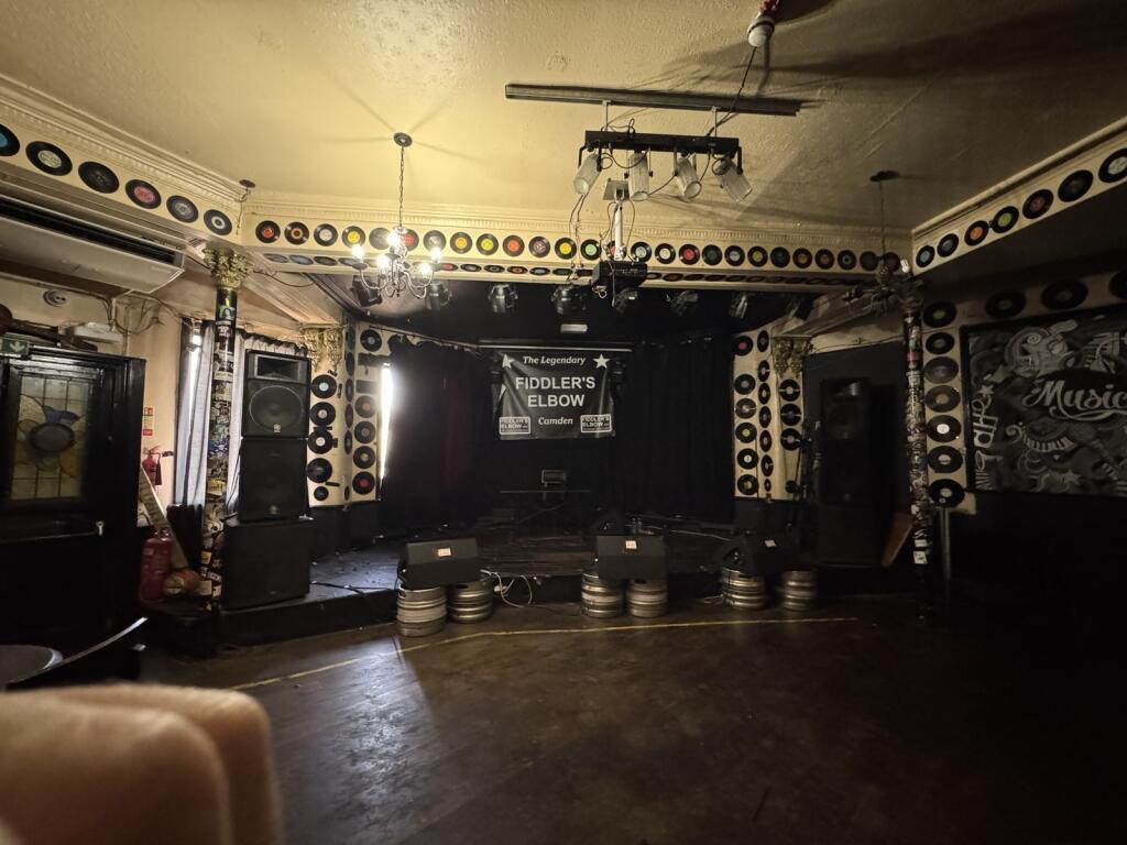 A small stage inside a pub with records adorning the walls 