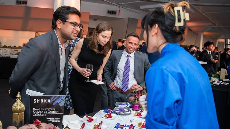 A chef presenting food to a group of three people