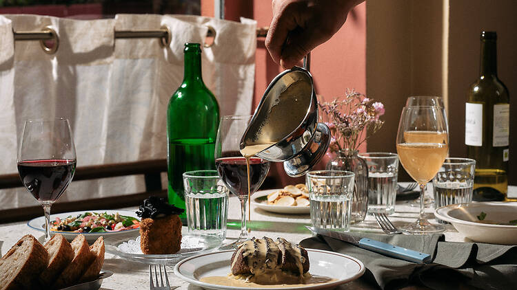 tarjoilija kaataa pippurikastiketta pihvin päälle ravintolassa Nolita