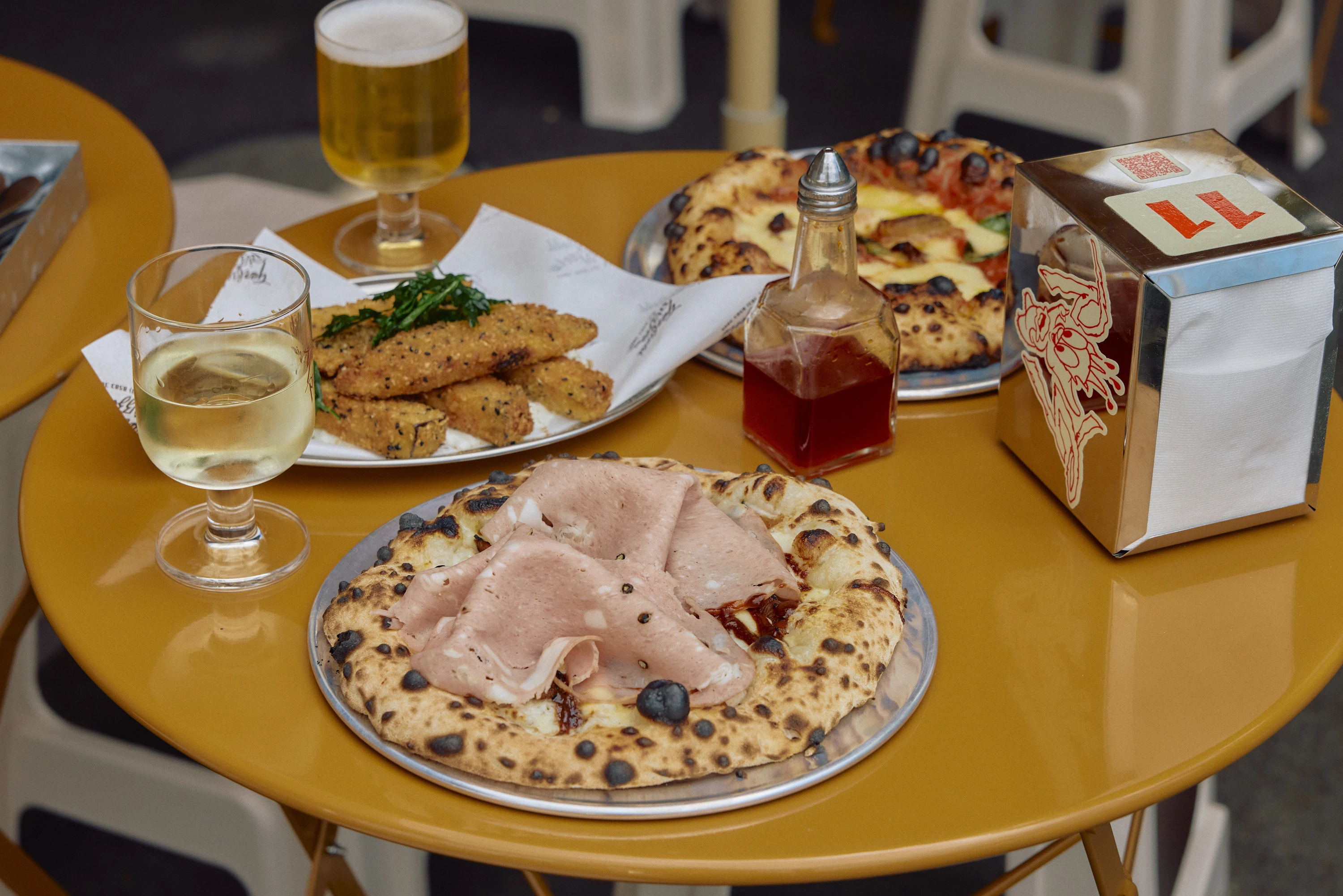 A table laden with pizzas and drinks.