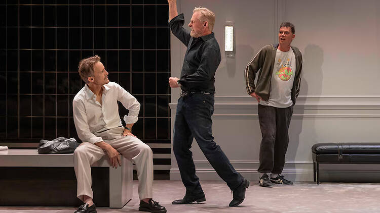 A male actor in black looking angry at another male actor wearing white