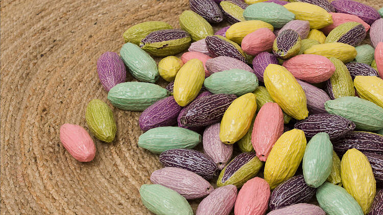 Glazed ceramic seeds in pastel colours on a jute mat 