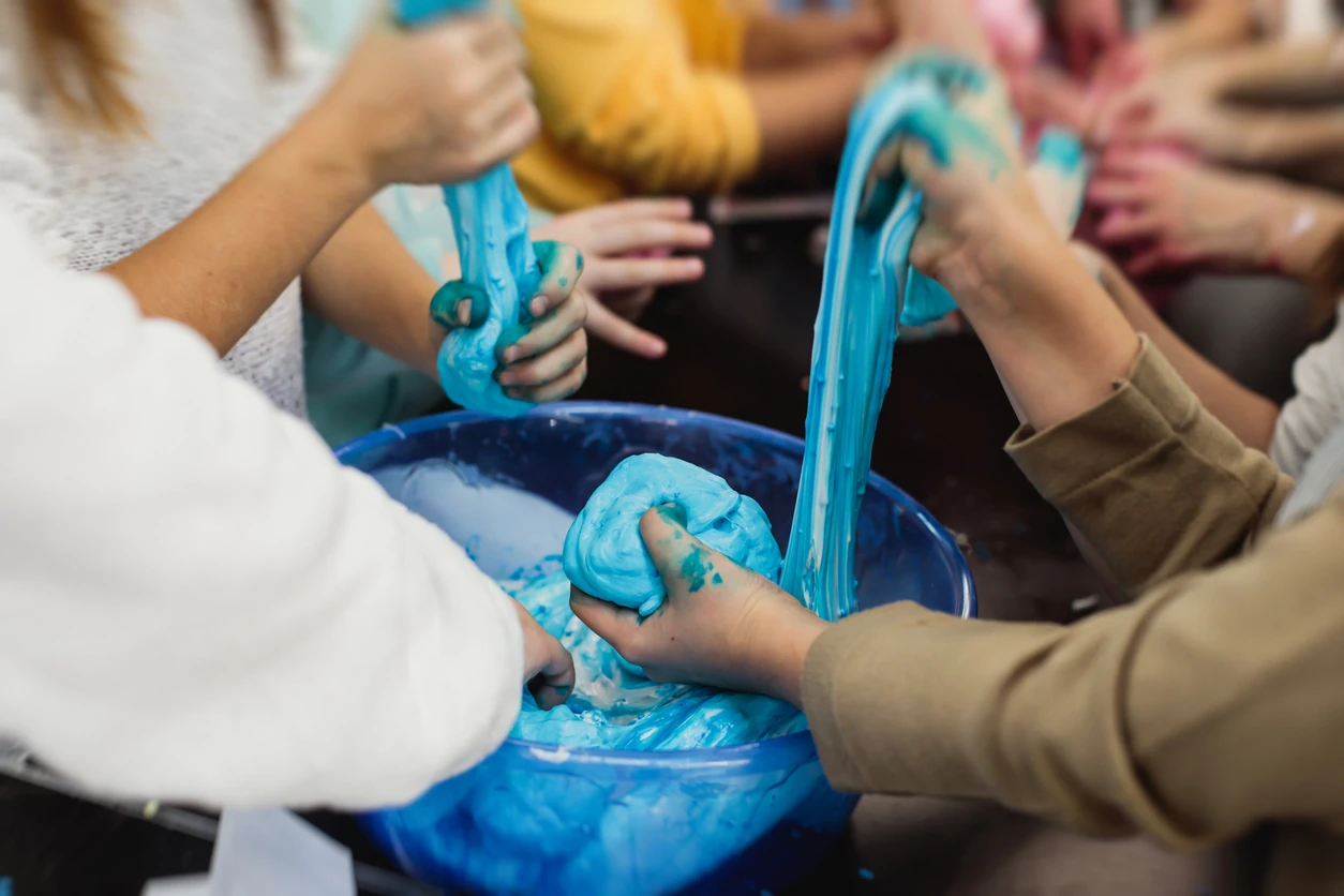 Group of kids making a multicoloured slime, pink, blue and white slime toy on kids birthday party, kid playing with slime, homemade slime