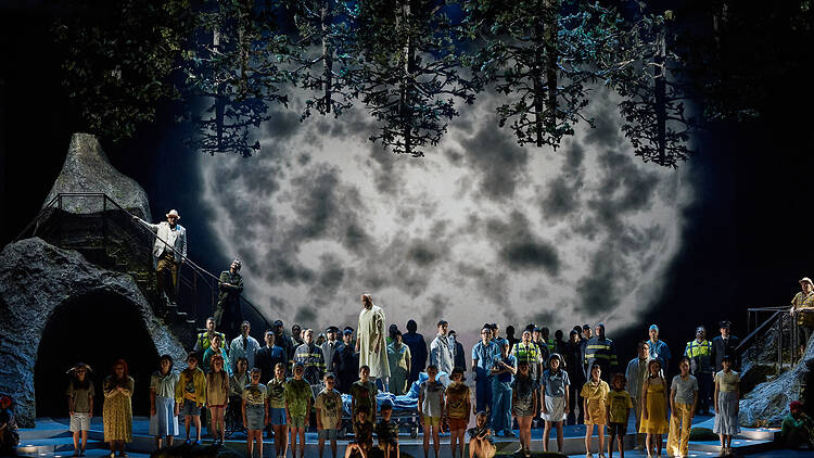 Large group of opera singers on the stage giant star looming behid them