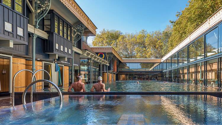 Two men relaxing in the main pool on a sunny day at Thames Lido in Reading