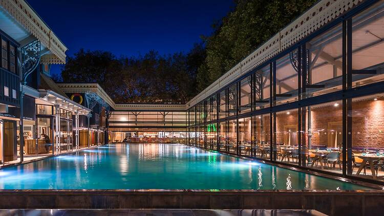 Night time shot of the main pool and restaurant area at Thames Lido in Reading