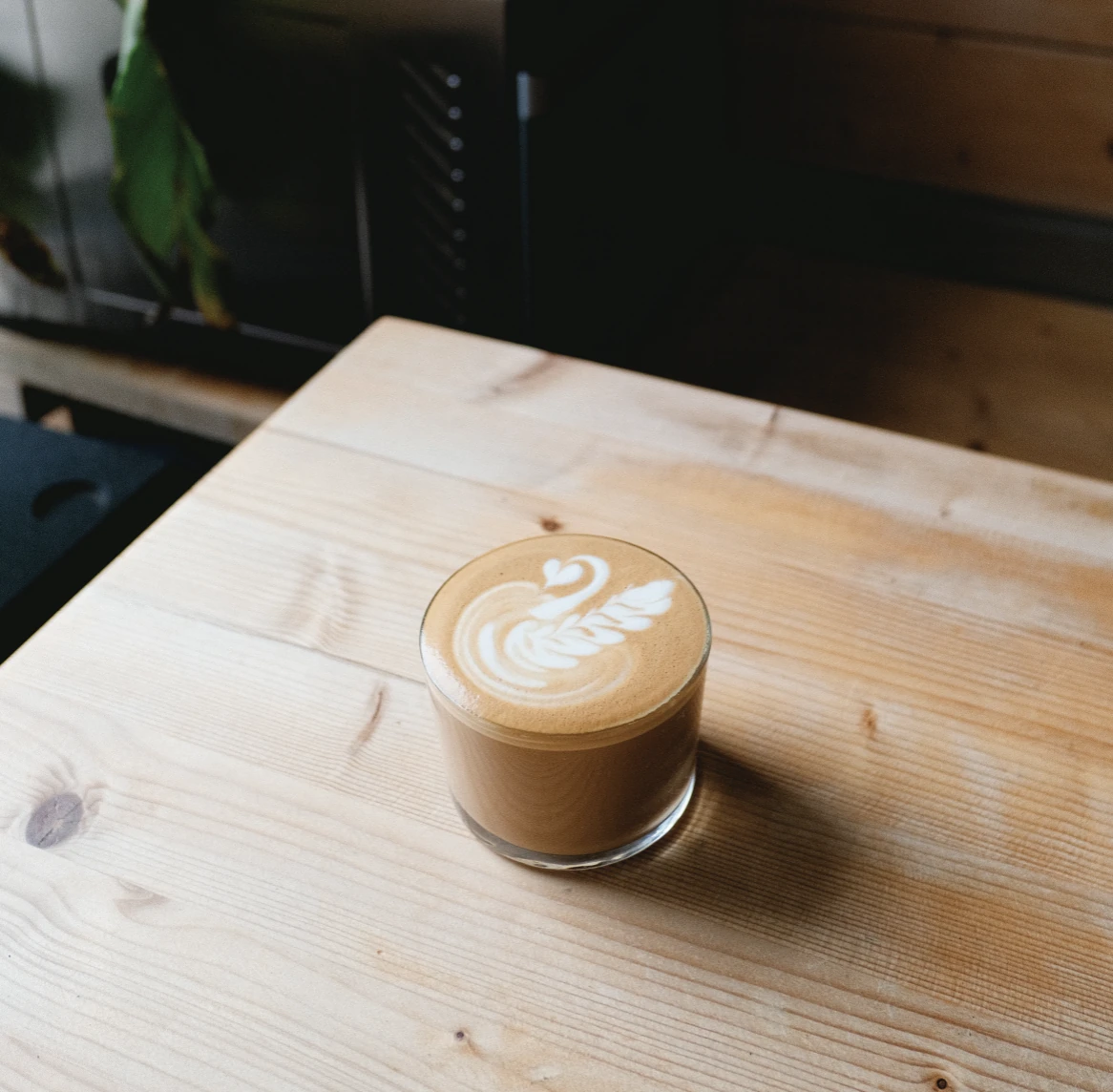 Coffee featuring latte art swan on wooden table