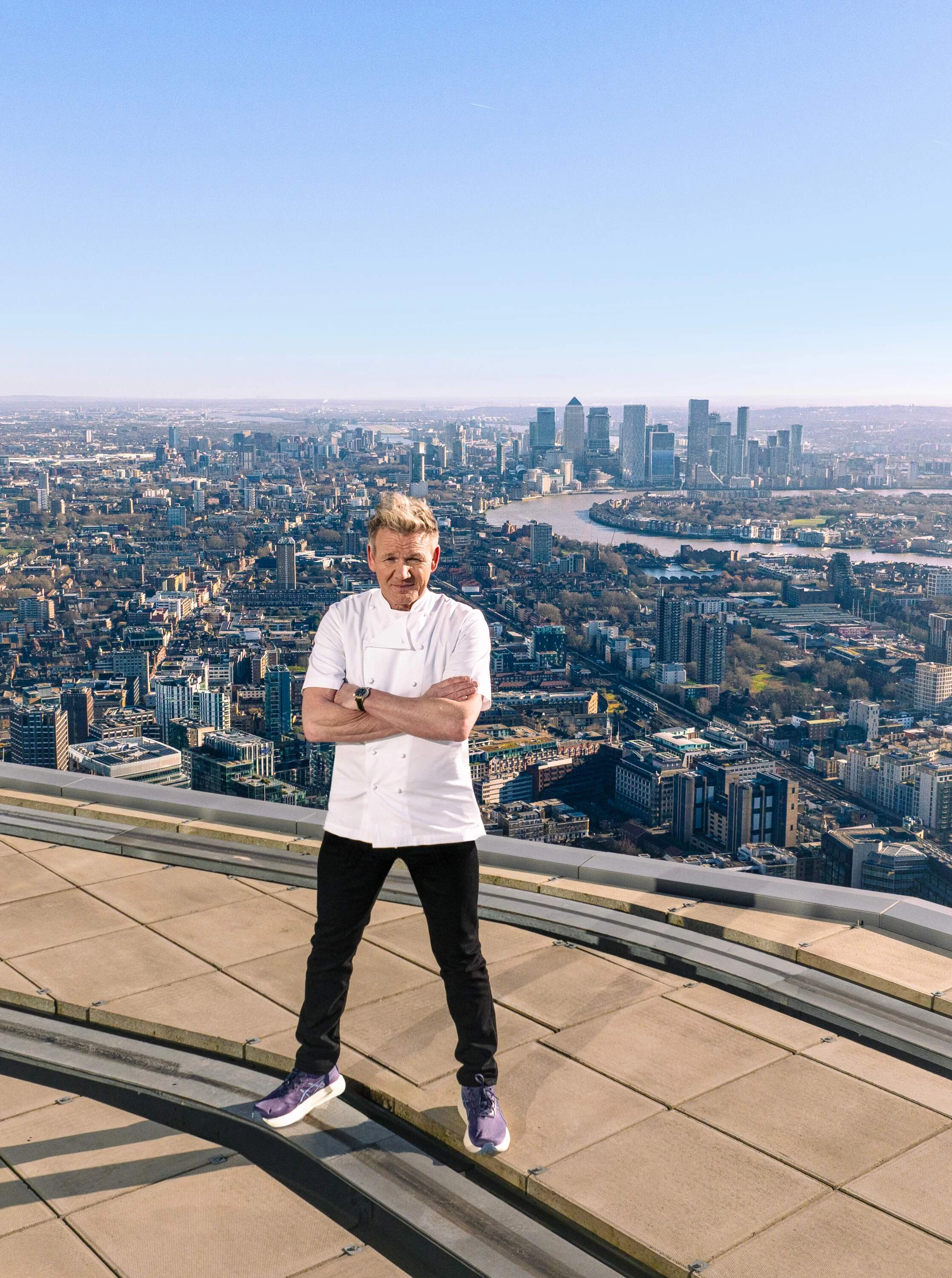 Chef Gordon Ramsay standing on a rooftop with London behind
