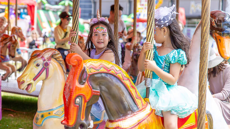 Ingenia Holiday Parks Sydney Family Show Two little girls on a carousel with their faces painted