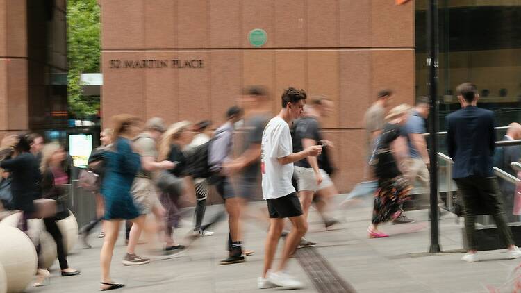 A crowd of people walking down a street next to a tall building