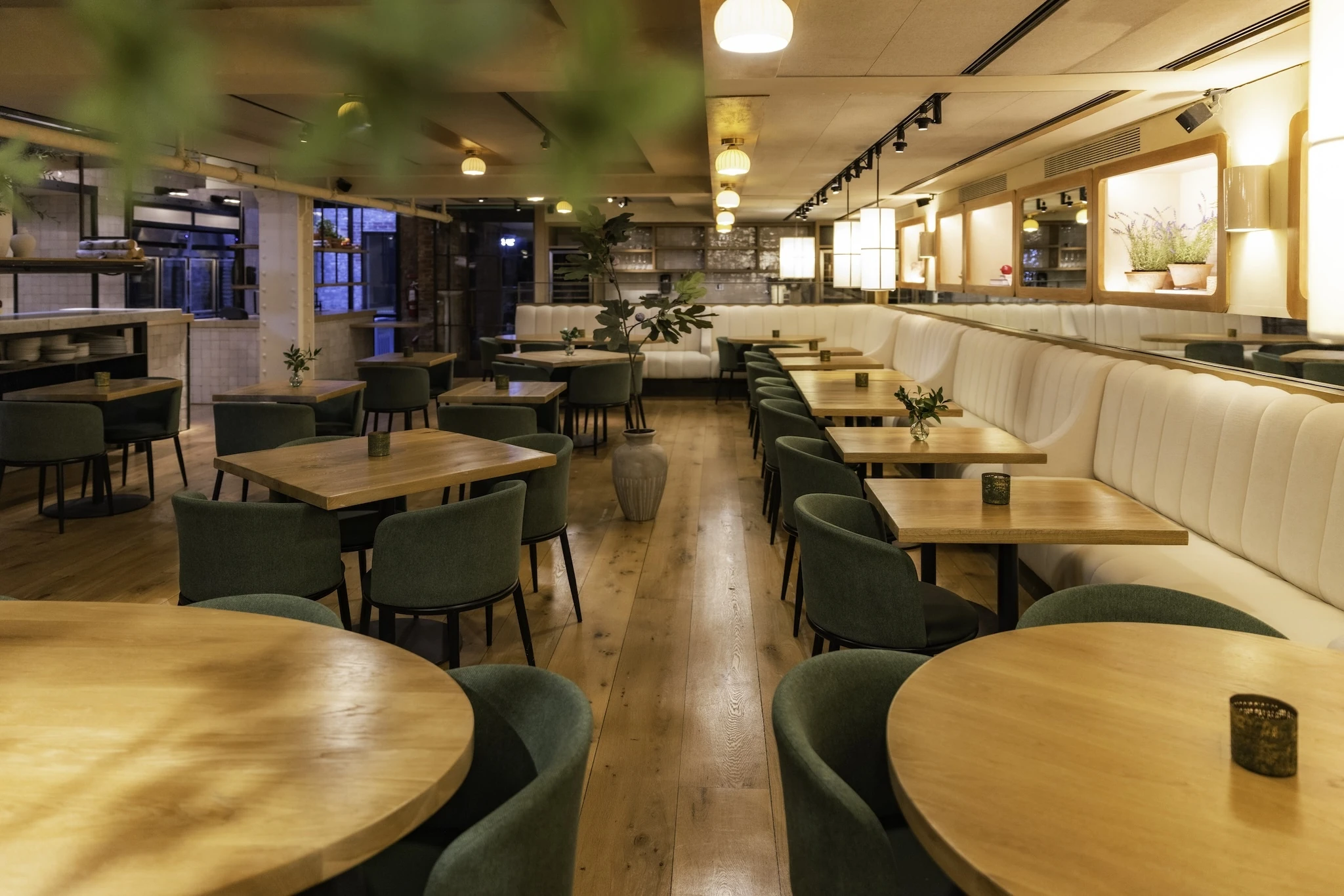 A dining room with green chairs, a white booth and glowing lights