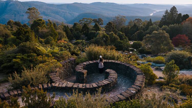 A woman overlooking the views of a large garden and the mountains in the background