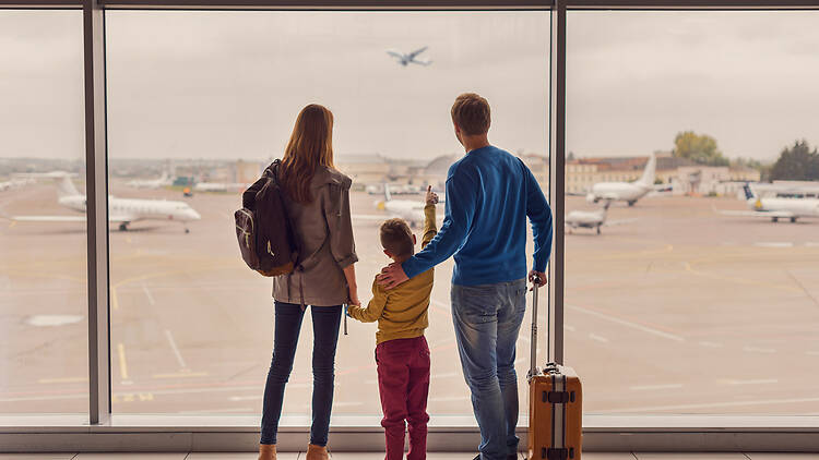 Such large aircraft. Back view shot of young family with luggage standing near window in airport before boarding