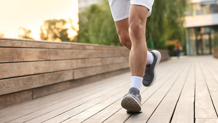 Athletic man in sneakers running outdoors, closeup