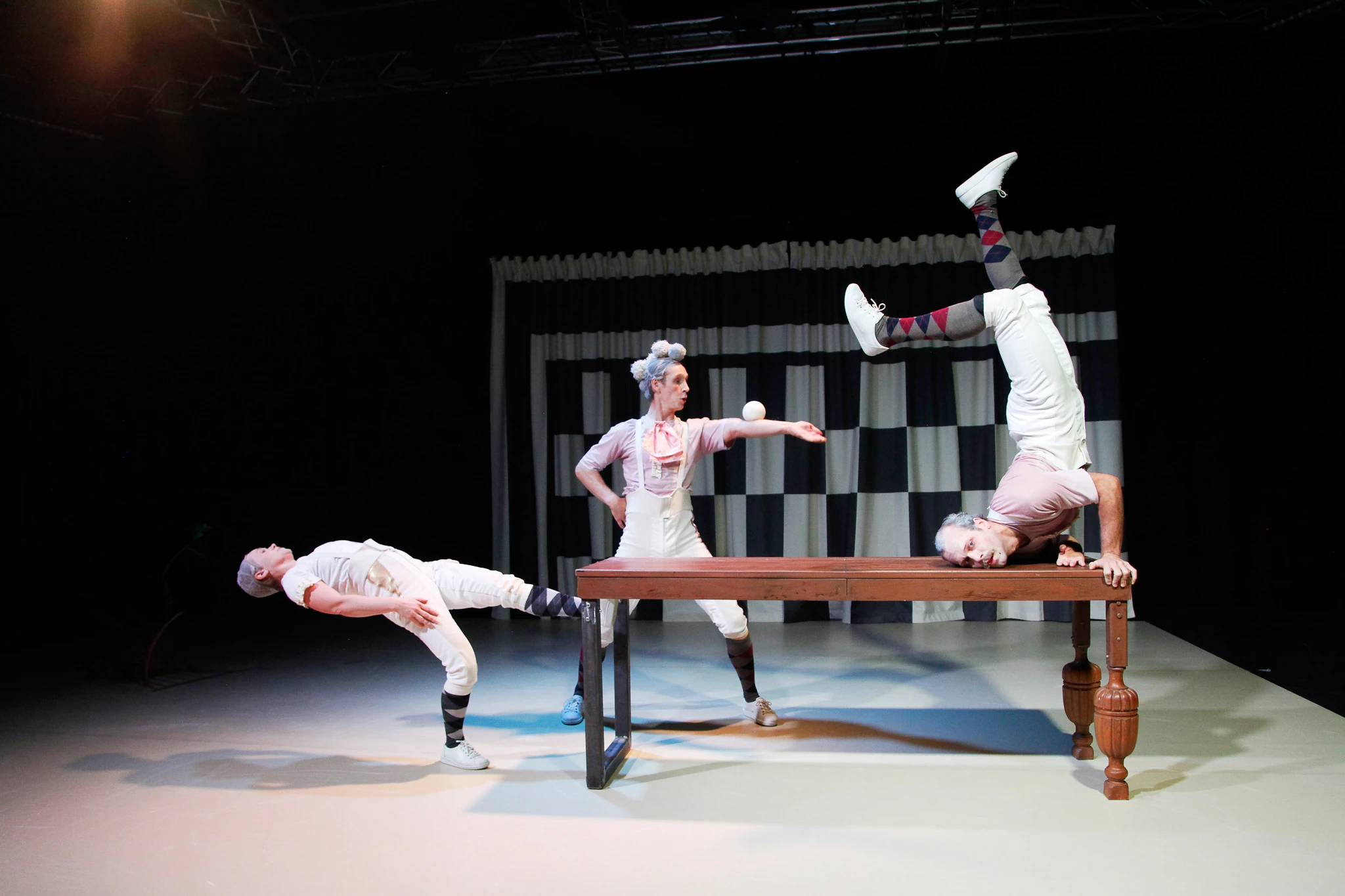 Kolme akrobaattia tasapainoilee p&ouml;yd&auml;n ymp&auml;rill&auml;