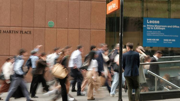 A group of people walking down a street next to a building