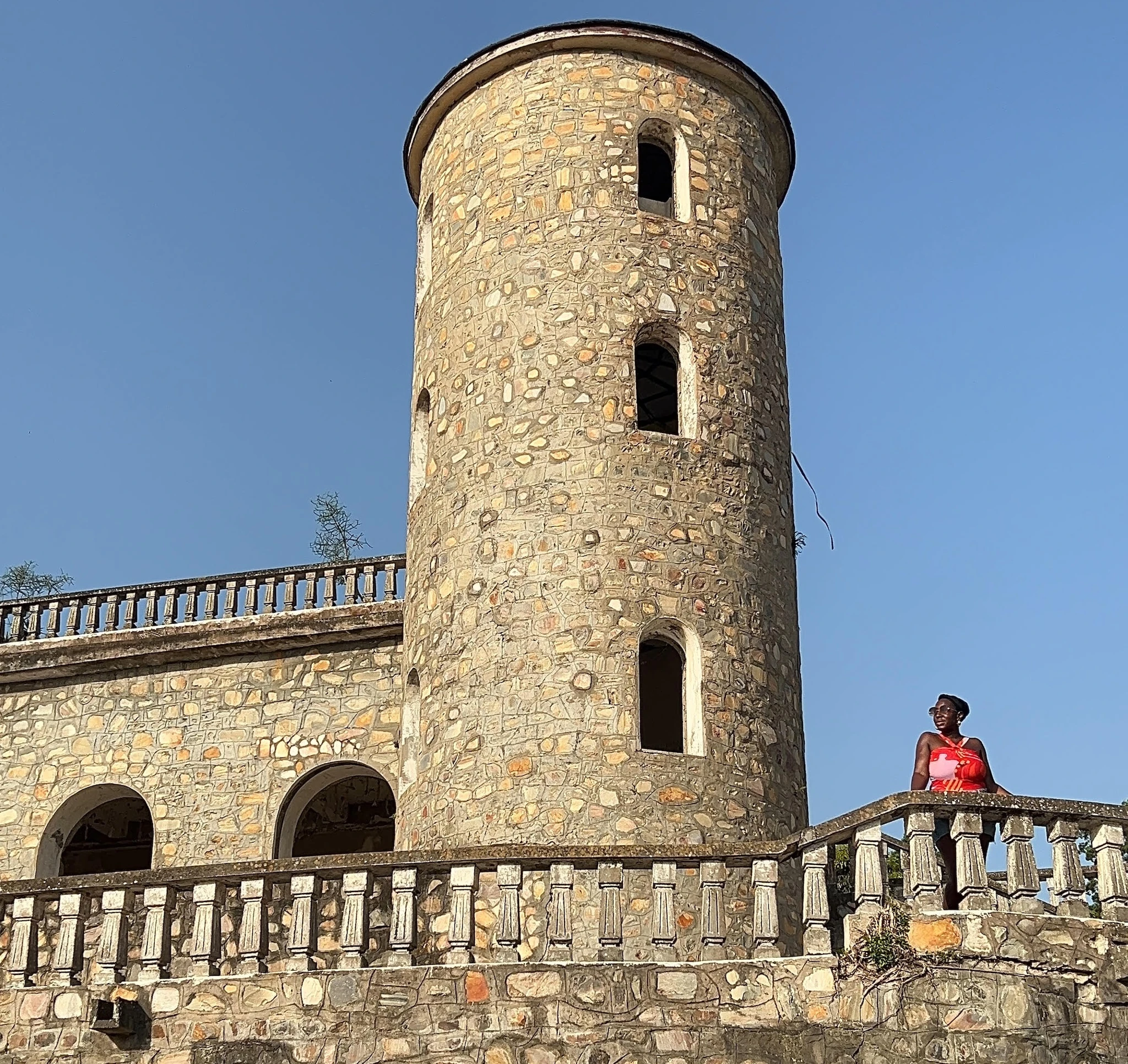 A woman stands by a tower in Togo