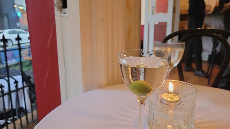 Two Martini cocktails on a table with a candle