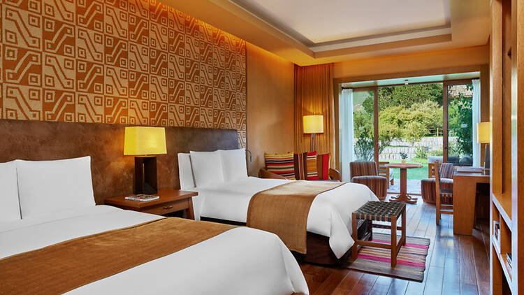 A hotel room with double beds and a yellow and white woven wallpaper