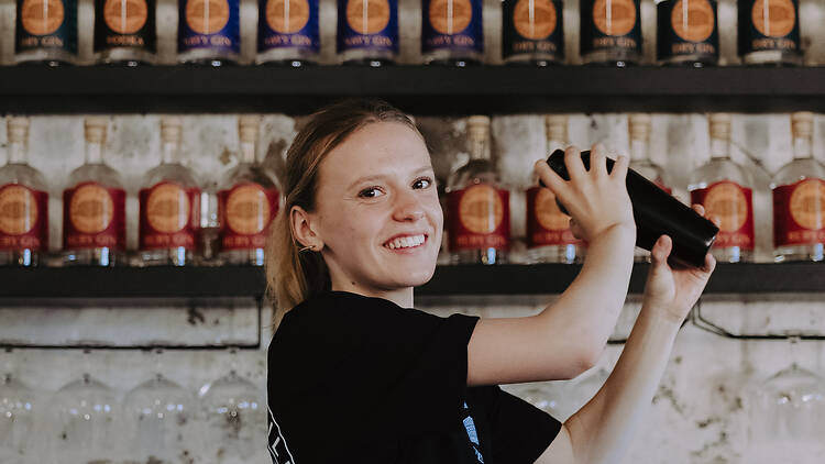 female bartender shakes a cocktail behind a bar