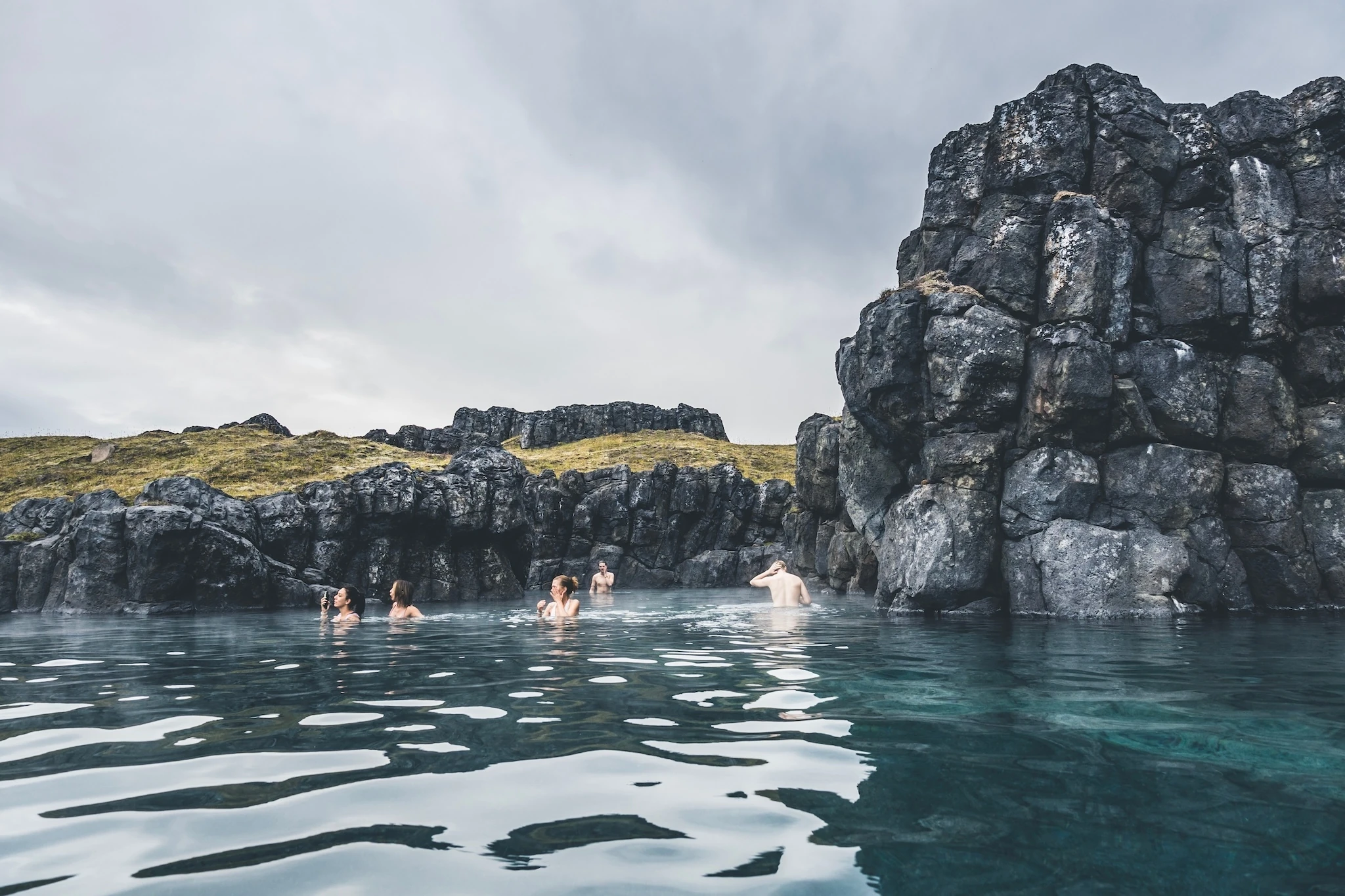  Sky Lagoon in Iceland. Tourists enjoying geothermal spa with heated water during cold day