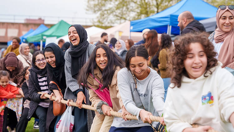 A group of women and girls play tug-of-war at London Eid Festival